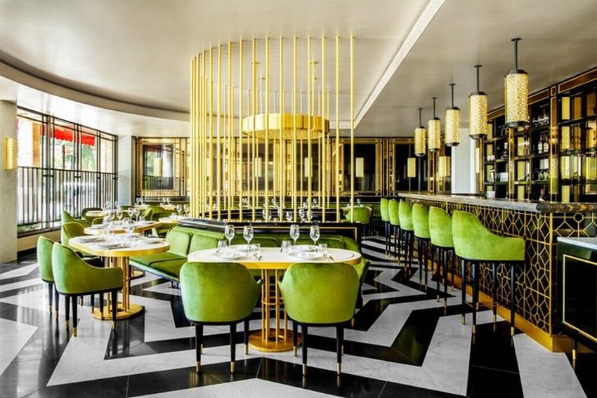 Thiết kế thi công nội thất nhà hàng đẳng cấp với quầy bar sang trọng, ghế bọc nỉ xanh và ánh sáng vàng nổi bật.