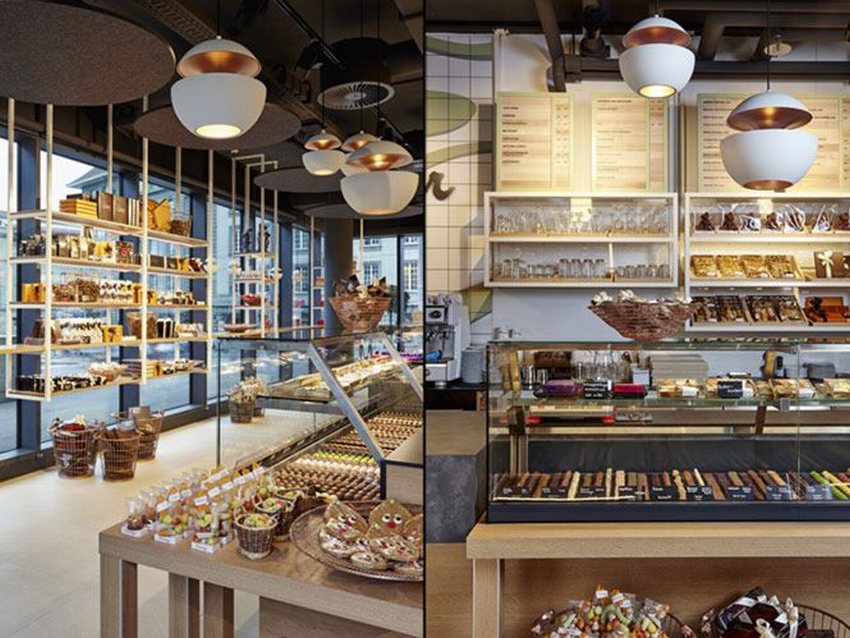 Thiết kế nội thất khu vực ngồi Baker Café với bàn gỗ, ghế nệm và tranh treo tường hiện đại.