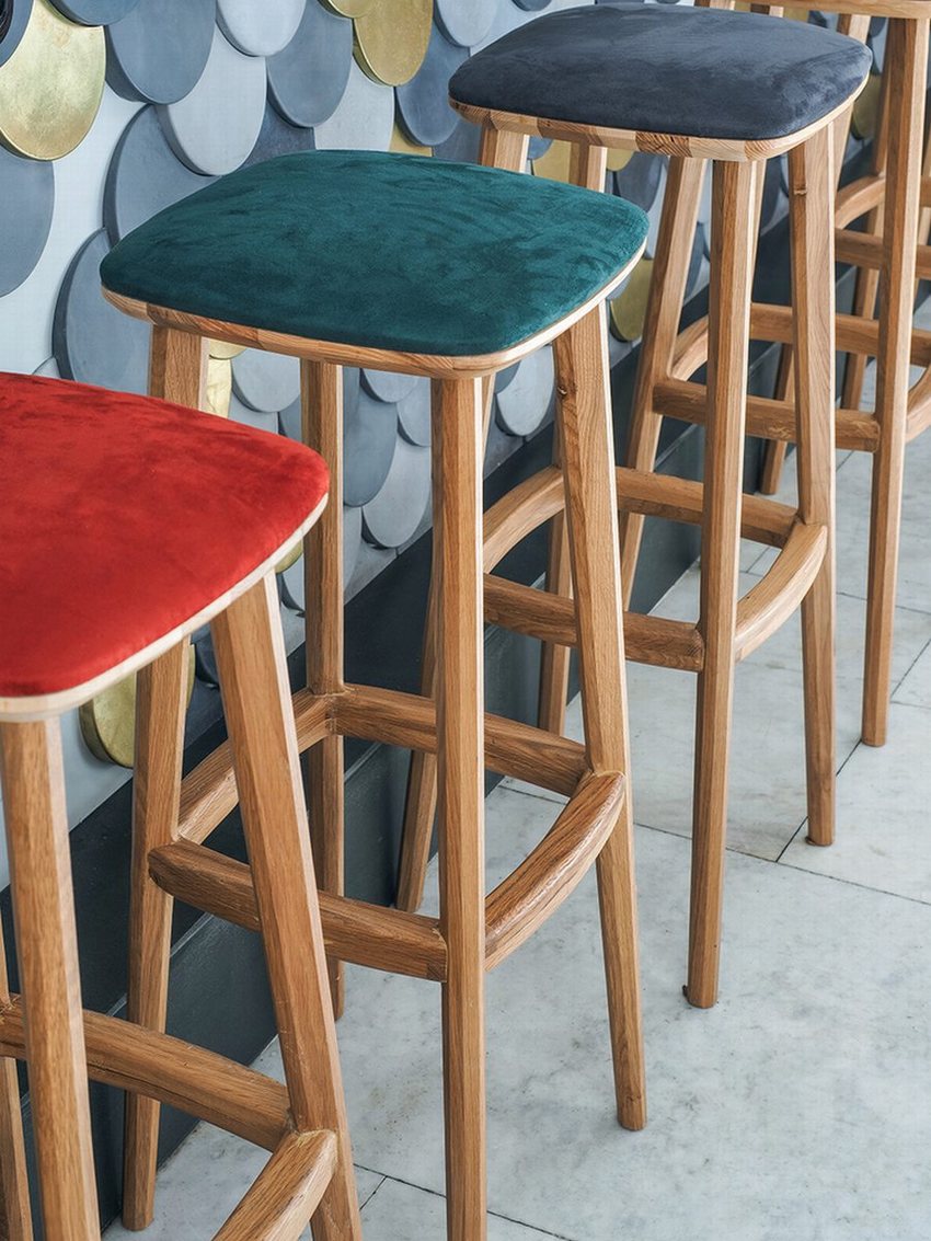Thiết kế cafe bar sang trọng, quầy bar đá trắng với ghế gỗ bọc nệm nhiều màu, trang trí sofa đỏ và kệ rượu gỗ hiện đại.