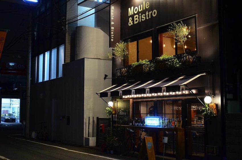 Thiết kế quán cafe phong cách bistro châu Âu, mặt tiền nổi bật với ánh đèn vàng ấm áp, mái hiên kẻ sọc và ban công xanh tạo điểm nhấn thu hút về đêm.