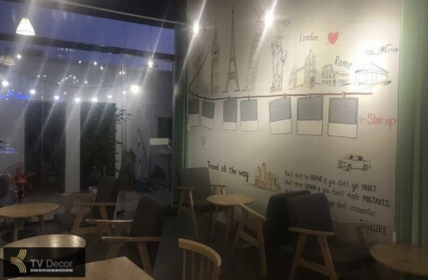 Không gian quán cafe khung thép được trang trí trẻ trung với tranh tường nghệ thuật lấy cảm hứng từ du lịch và khởi nghiệp, kết hợp bàn ghế gỗ kiểu Bắc Âu, tạo nên góc ngồi thoải mái và ấm cúng.