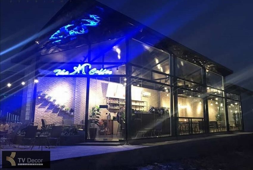 Thiết kế thi công quán cafe khung thép hiện đại, kiến trúc kính độc đáo, nổi bật với ánh sáng buổi tối.