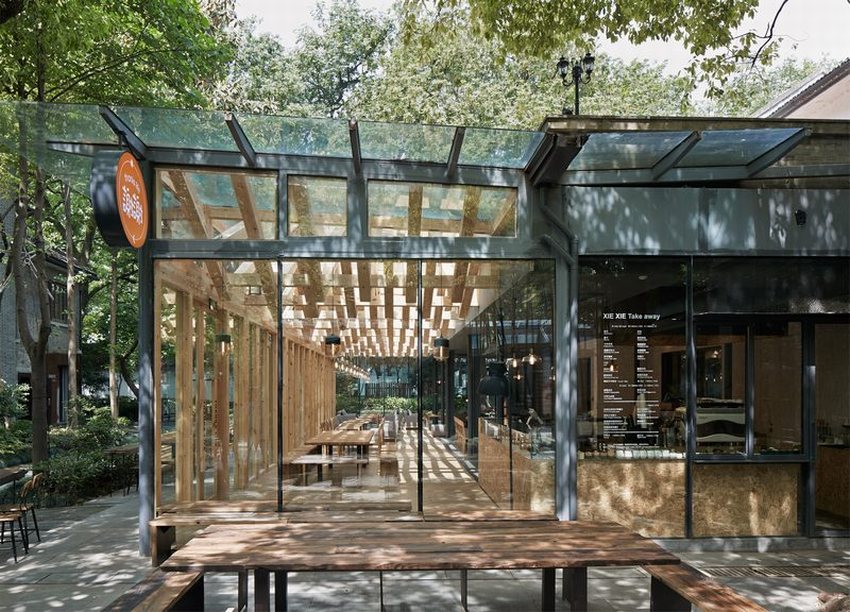 Thiết kế thi công quán cafe khung thép hiện đại với không gian kính trong suốt, kết hợp gỗ và ánh sáng tự nhiên, mang lại cảm giác thoáng đãng giữa thiên nhiên.