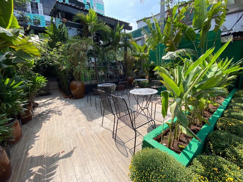 Không gian quán cafe sân vườn thoáng đãng với nhiều cây xanh, bàn ghế ngoài trời hiện đại, mang lại cảm giác gần gũi thiên nhiên và thư giãn.