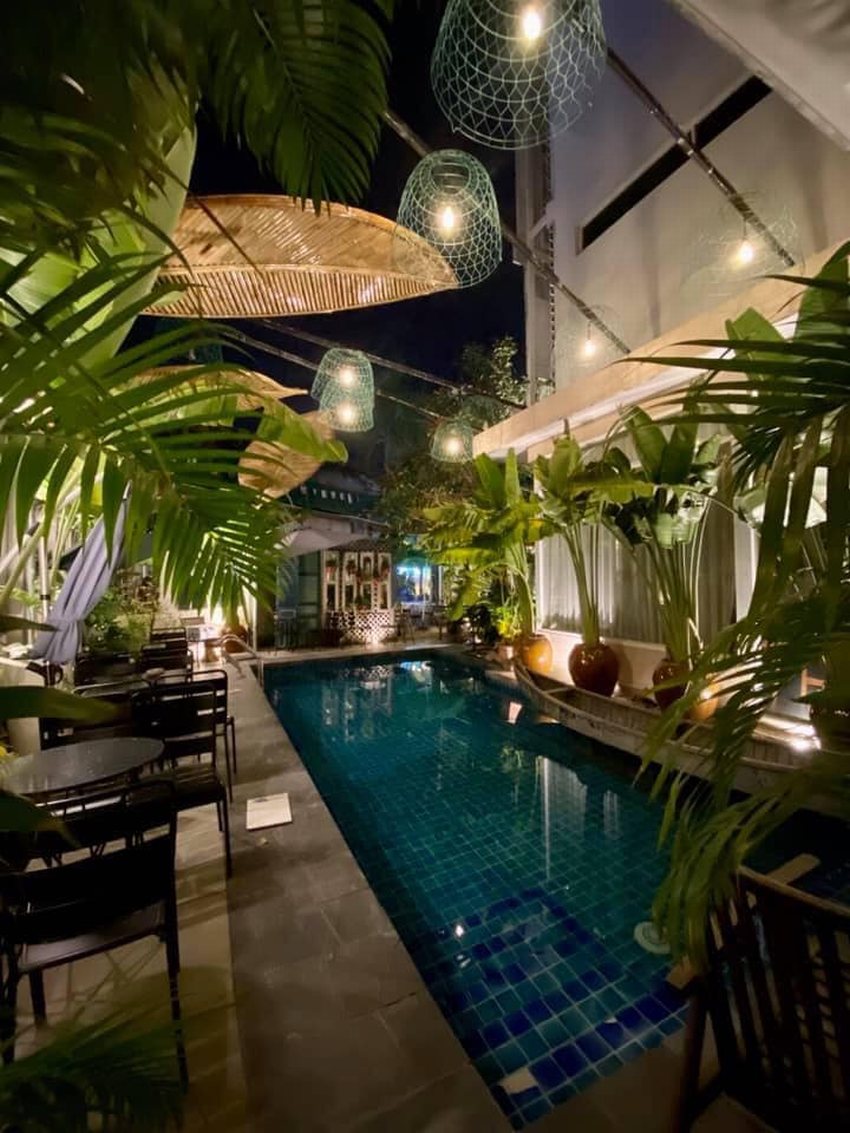 Không gian quán cafe sân vườn về đêm với hồ bơi xanh mát, ánh đèn trang trí lung linh và cây xanh bao quanh tạo vẻ đẹp sang trọng, lãng mạn.