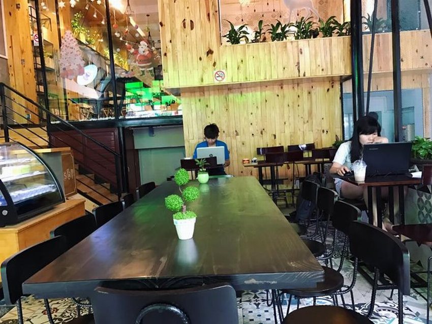 Thiết kế nội thất quán cafe trà sữa đẹp với kệ gỗ trang trí, ánh sáng vàng ấm cúng và không gian hiện đại.