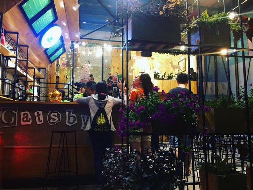 Quầy order của Gatsby Tea & Coffee Express với thiết kế gỗ ấm cúng, màn hình menu điện tử hiện đại, khách hàng xếp hàng gọi món.