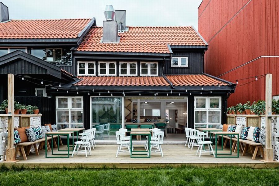 Thiết kế nhà hàng ấm cúng với ghế xanh, bàn gỗ và ánh sáng đèn treo.