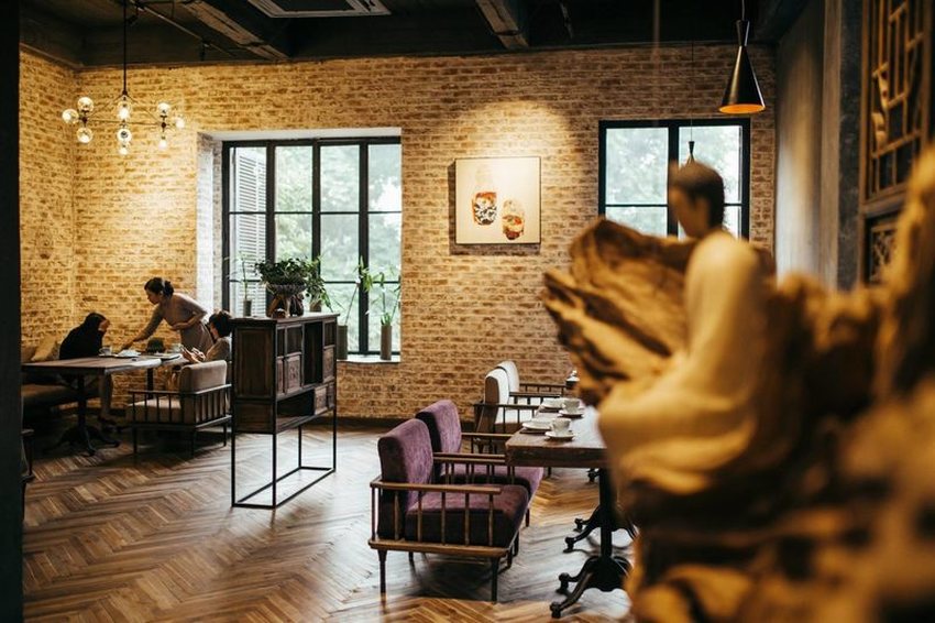Nhà hàng chay với tường gạch thô, nội thất gỗ mộc mạc và ánh sáng vàng ấm, mang lại cảm giác yên bình và gần gũi cho thực khách. 