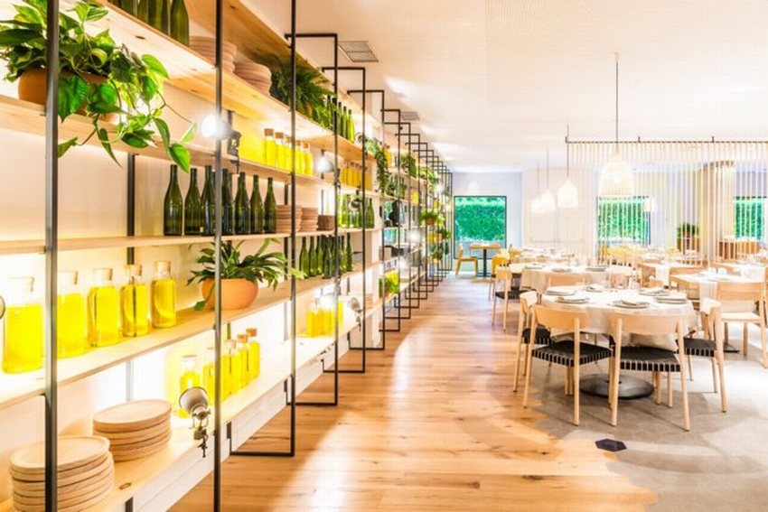 Không gian nhà hàng hải sản hiện đại với kệ trưng bày rượu vang, chai decor và cây xanh, tạo điểm nhấn tự nhiên, tươi mới và thu hút thực khách.