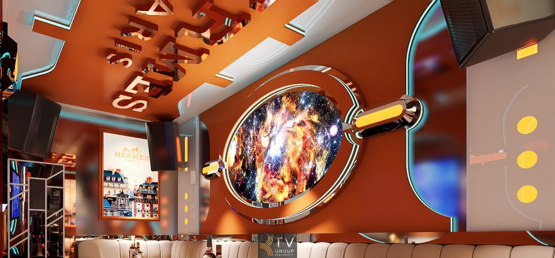 Thiết kế phòng karaoke chủ đề Hermès Paris với tông màu cam sang trọng, tường trang trí hình học hiện đại, hệ đèn LED viền và màn hình karaoke lớn tạo không gian KTV cao cấp và nổi bật.