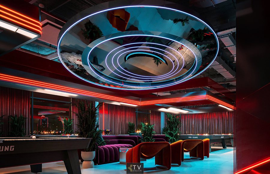 Góc nghiêng khu vực lounge và bàn bida với công năng chờ, thư giãn. Âm thanh bố trí âm trần, ánh sáng LED tròn trang trí kết hợp đèn viền. Decor hiện đại, vật liệu kim loại, kính, gỗ, nỉ. Gam màu đỏ – tím – xanh chủ đạo. Bàn bida tiêu chuẩn, ghế sofa cong, trần nghệ thuật, sàn phẳng, tranh ảnh tối giản.