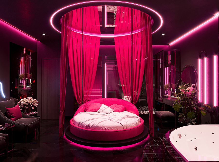 Phòng khách sạn Neon Velvet với giường tròn có rèm, ánh sáng hồng tím, nội thất uốn cong sang trọng – thiết kế thi công bởi KTV Group.