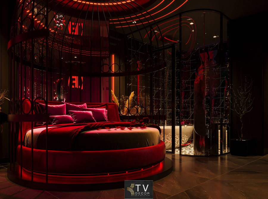 Phòng khách sạn chủ đề tình yêu phong cách Dark Romantic với giường tròn, ánh sáng mood đỏ và nội thất sang trọng tạo trải nghiệm lãng mạn, cuốn hút.