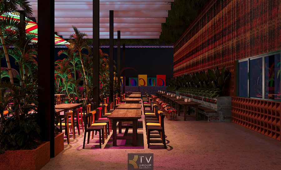 Bố cục không gian tổng thể Góc thiết kế thể hiện khu vực dãy bàn dài trung tâm, bố trí theo trục thẳng, tạo cảm giác gọn gàng, dễ phục vụ. Lối đi rộng giúp di chuyển thuận tiện, phù hợp nhà hàng quy mô lớn.  Khu bàn ăn & ghế ngồi Bàn gỗ dài kết hợp ghế nhiều màu sắc tạo sự sinh động, đúng tinh thần Coco Garden. Cách bố trí này phù hợp nhóm đông người, tiệc sinh nhật, liên hoan, khách gia đình hoặc khách du lịch.  Hệ mái che & trần Mái che dạng lam kết hợp vật liệu sáng màu giúp lấy sáng tự nhiên ban ngày, giảm cảm giác bí bách. Thiết kế bán mở giúp không gian luôn thoáng, nhưng vẫn đảm bảo che chắn thời tiết.