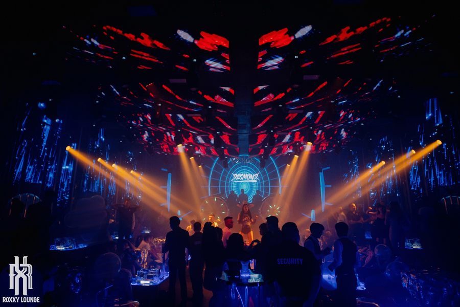 Không gian lounge bar nhìn từ trên cao với ánh sáng sân khấu rực rỡ, thể hiện quy mô lớn và khả năng thu hút đông khách trong mô hình kinh doanh giải trí hiện đại.