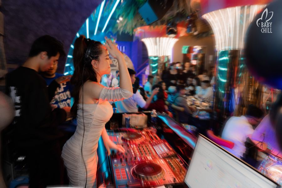 Không gian nhà hàng lounge bar hiện đại với khu vực DJ trung tâm, ánh sáng LED nhiều màu sắc tạo cảm giác sôi động, thu hút khách hàng trẻ trải nghiệm dịch vụ giải trí kết hợp ăn uống.